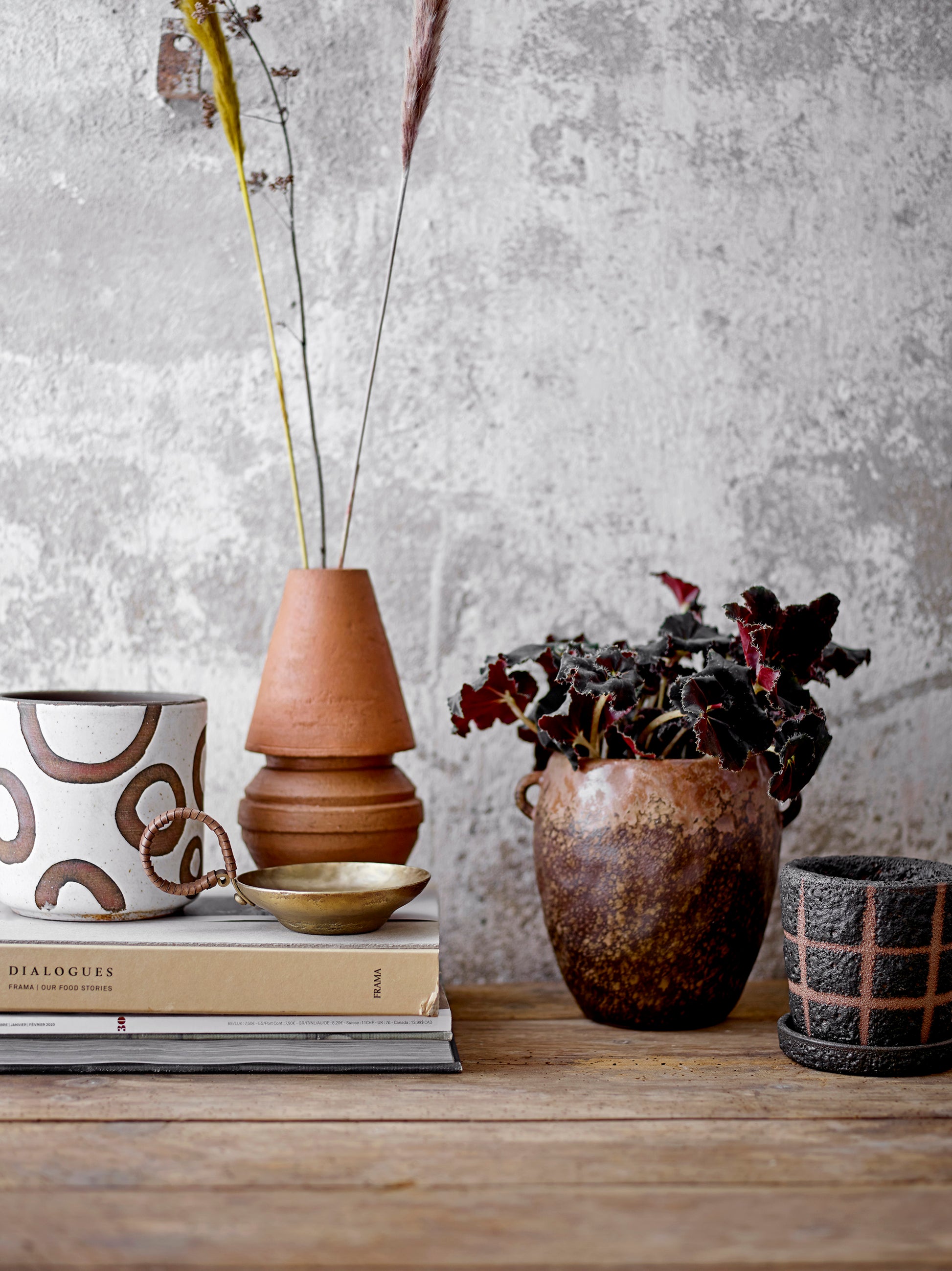 Decorative items including a mug, books, and vases on a wooden surface with a textured wall background.
