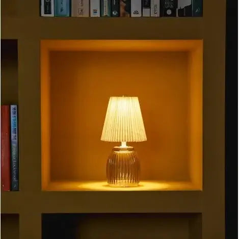 Small lamp with a light amber glass base on a wooden surface against a wall