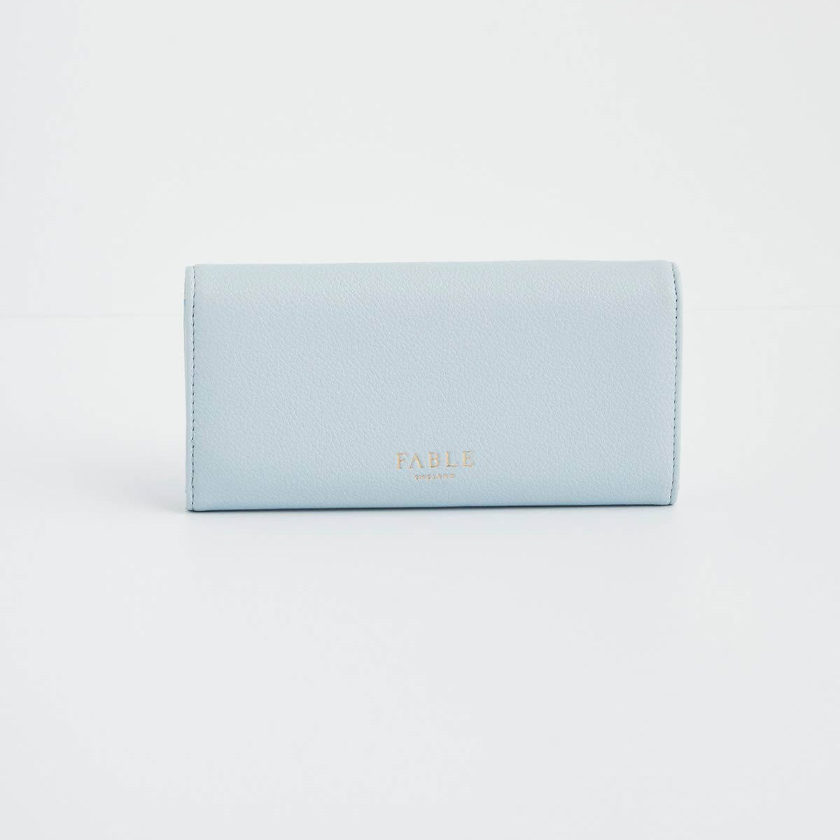 A light blue leather wallet with gold foil 'FABLE LONDON' branding, photographed on a seamless white background.
