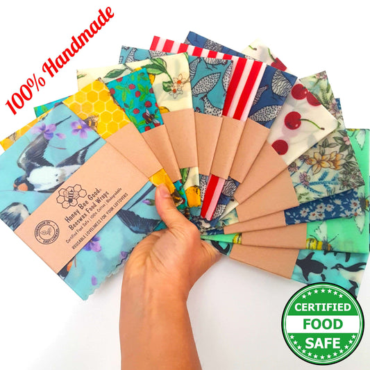 A hand holding a variety of beeswax food wraps with different patterns, displaying the text '100% Handmade' and 'CERTIFIED FOOD SAFE'.