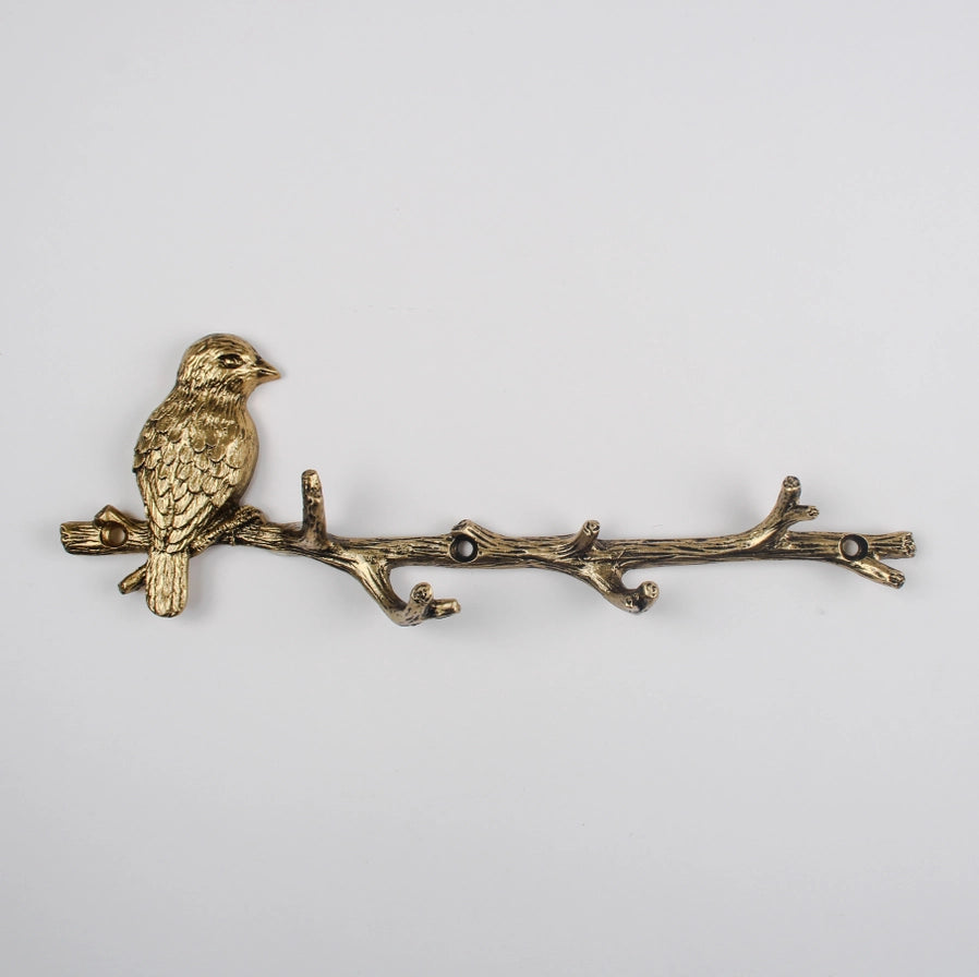 Bronze bird on a branch decorative item on a light gray background