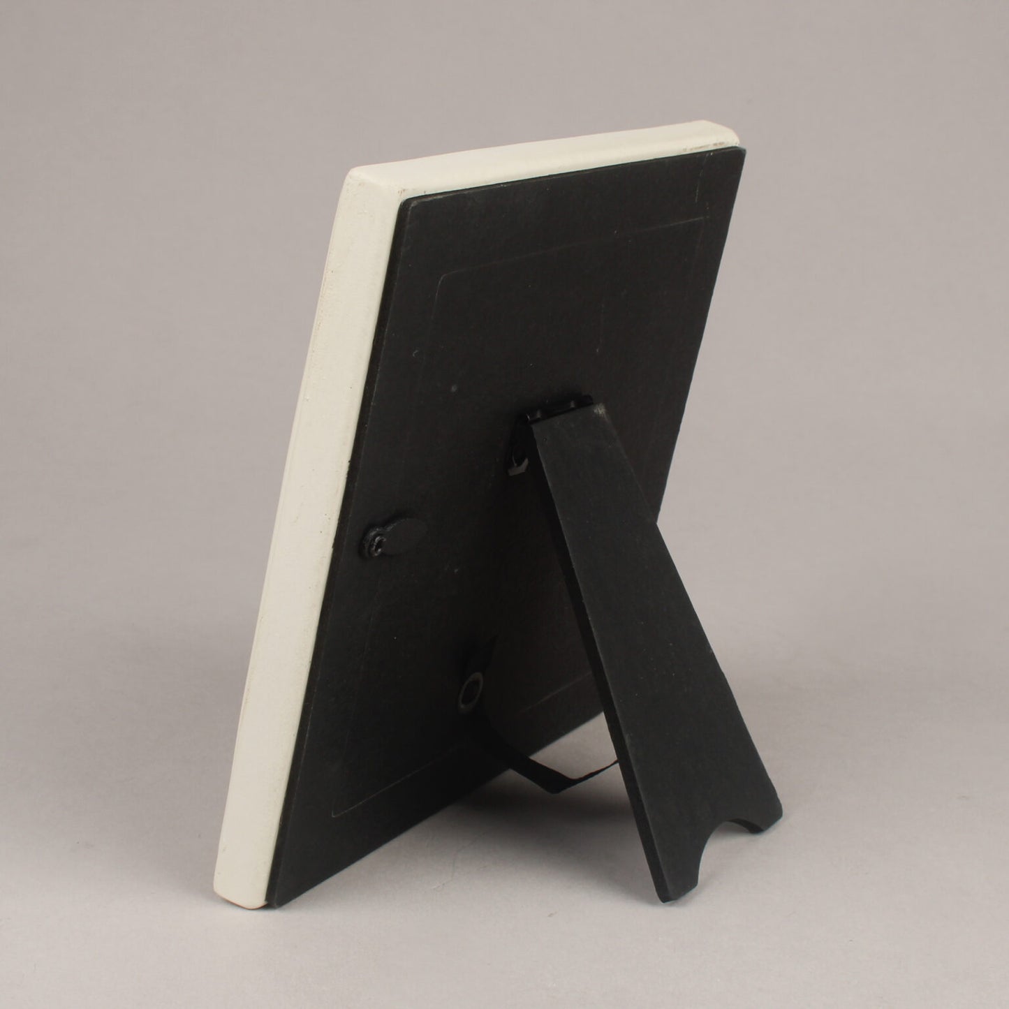 Black picture frame with a white back on a gray background