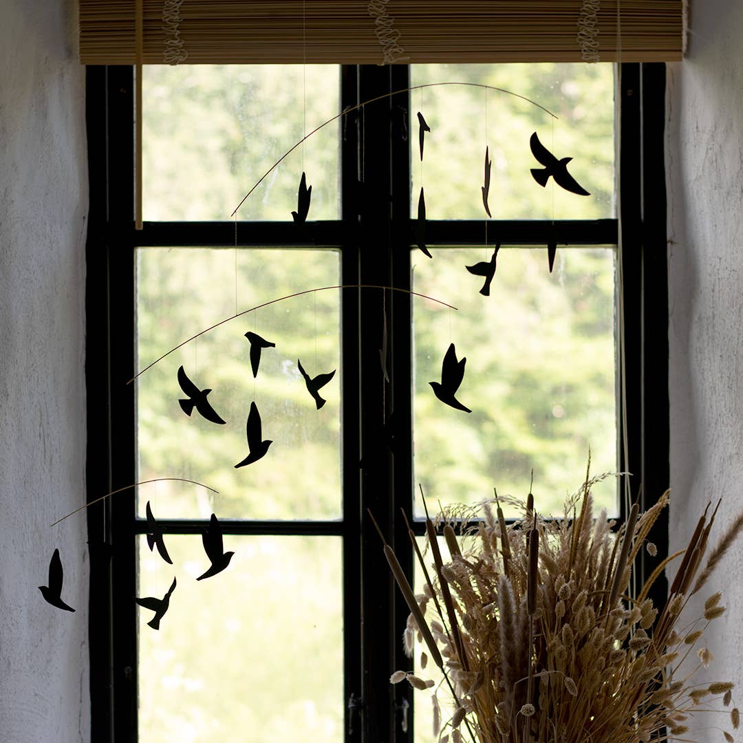 Black bird decals on a window with a blurred outdoor background