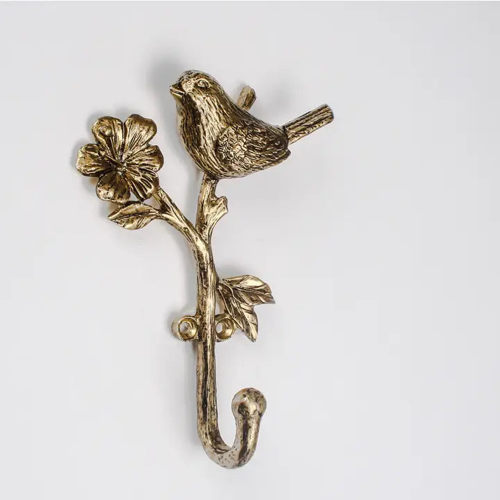 Decorative brass hook with bird and floral design on a white background