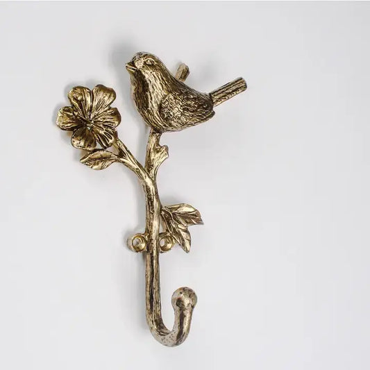 Decorative brass hook with bird and floral design on a white background
