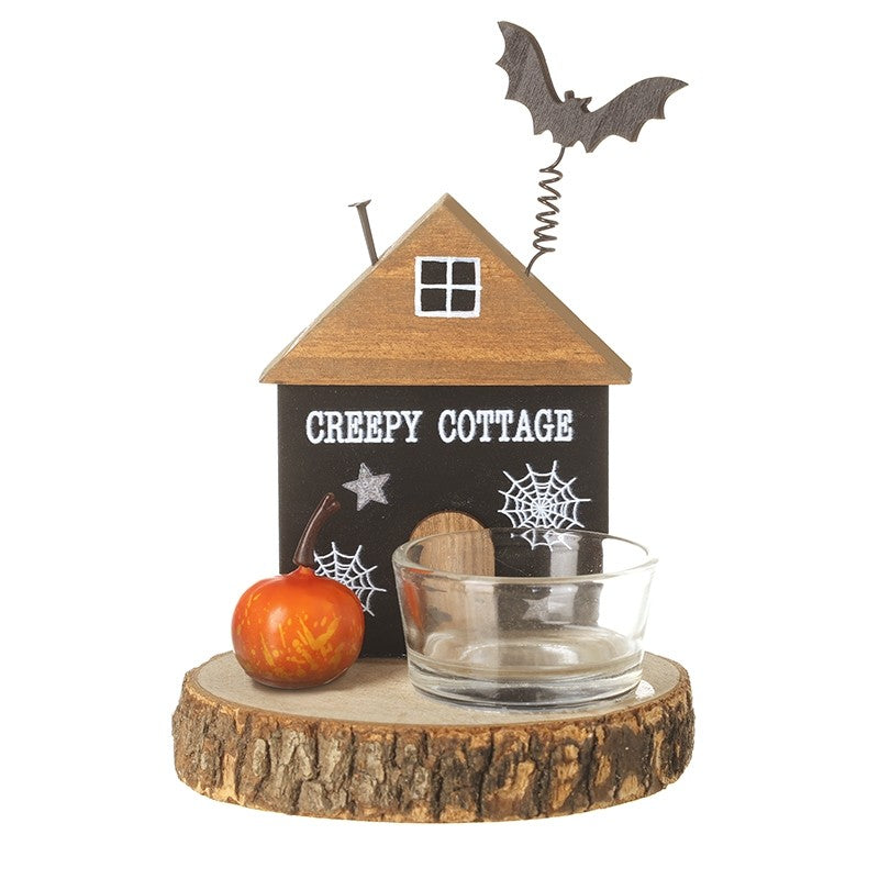Halloween-themed decorative wooden house with a 'Creepy Cottage' sign, small pumpkin, and glass bowl on a white background.