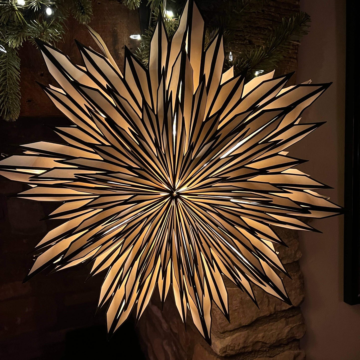 White and black paper decoration hanging on fireplace with light inside