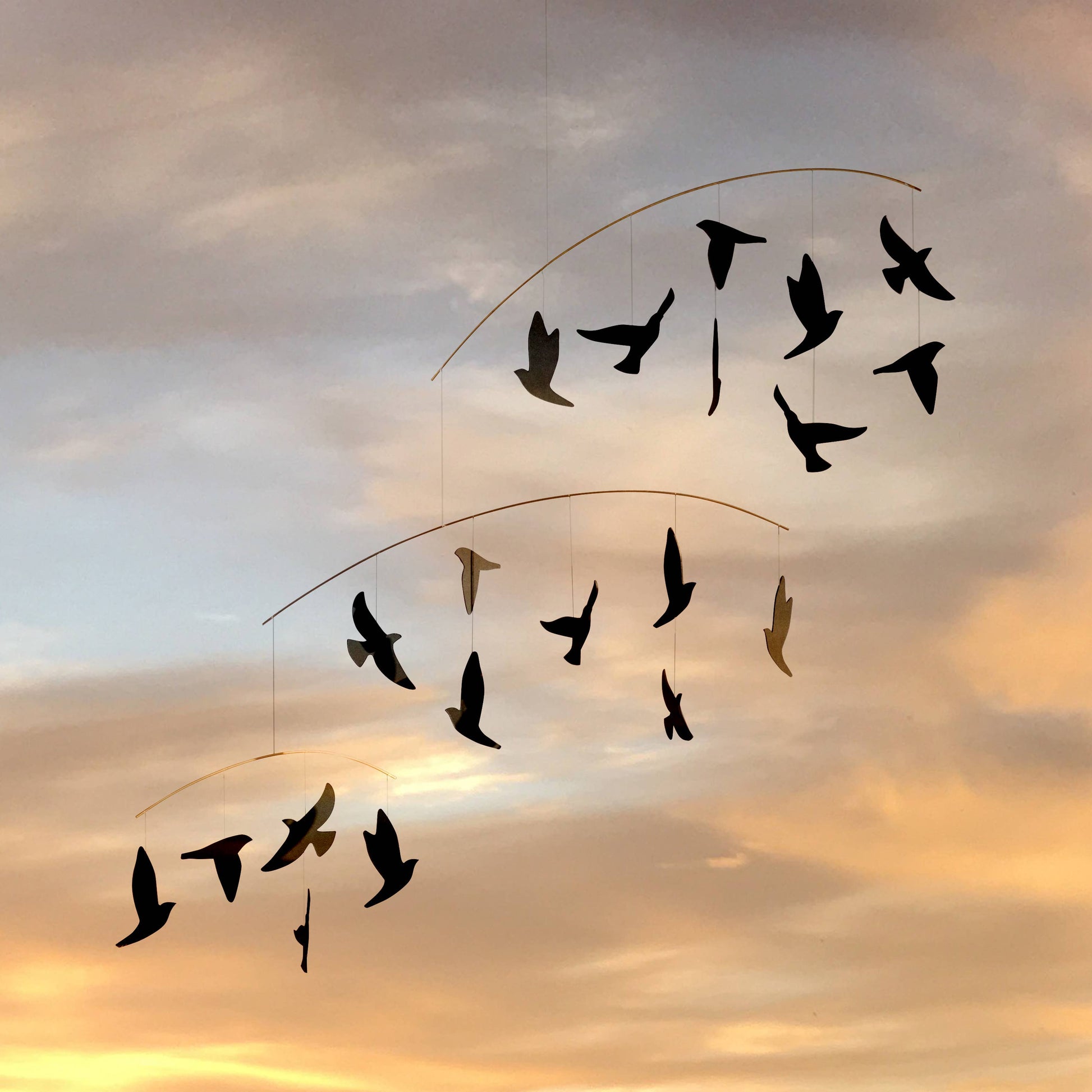 Decorative hanging mobile with bird shapes against a sunset sky