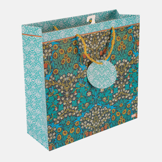 Floral patterned gift bag with a pom-pom tag on a white background