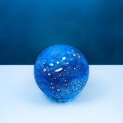 Blue glass sphere lamp with bubbles on a white surface and blue background