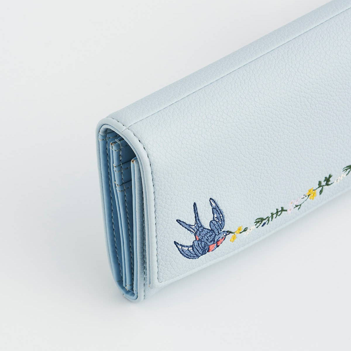 Light blue wallet with embroidered design on a white background