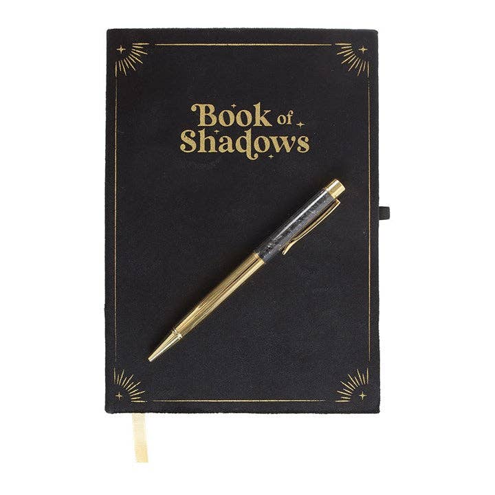 Black notebook titled 'Book of Shadows' with a gold pen on a white background