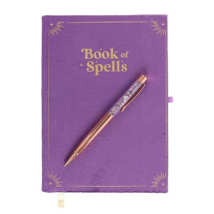 Purple notebook titled 'Book of Spells' with a rose gold pen on a white background