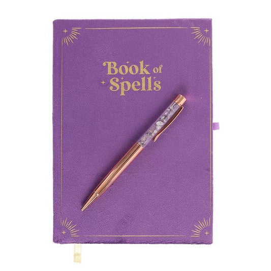Purple notebook titled 'Book of Spells' with a rose gold pen on a white background