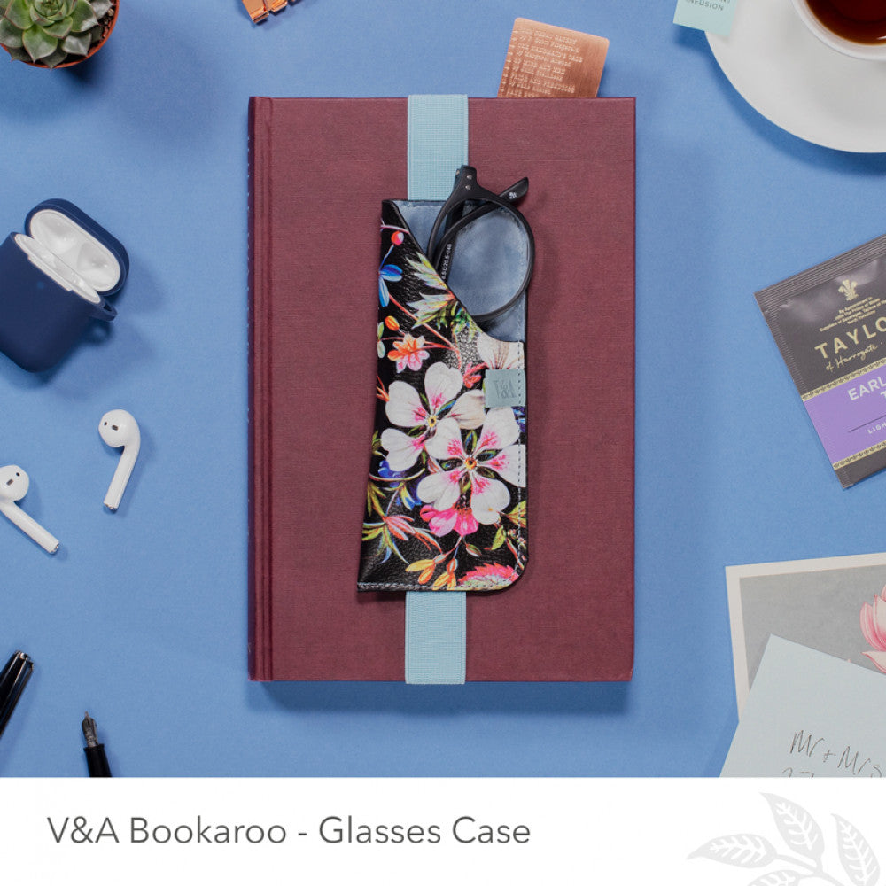 Glasses case with floral design on a blue surface with stationery items