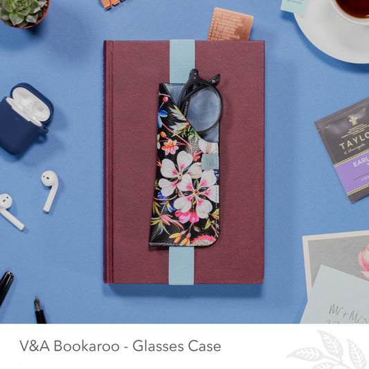 Glasses case with floral design on a blue surface with stationery items