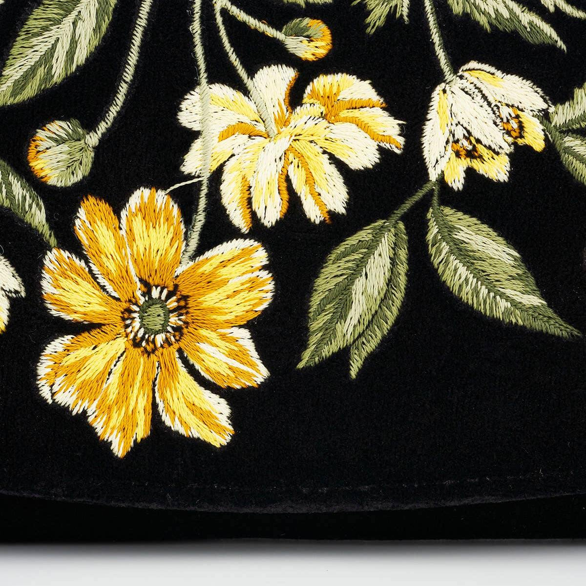 Close-up of a black fabric with yellow floral embroidery on a white background