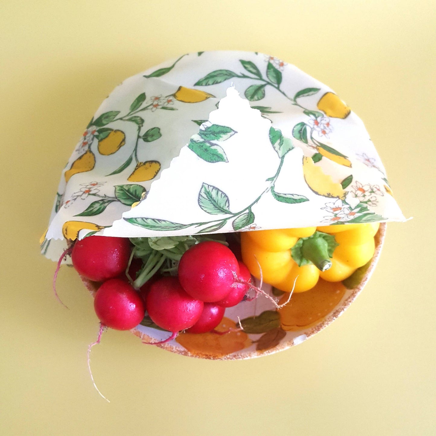 A bowl of vegetables partially covered with a wax food wrap