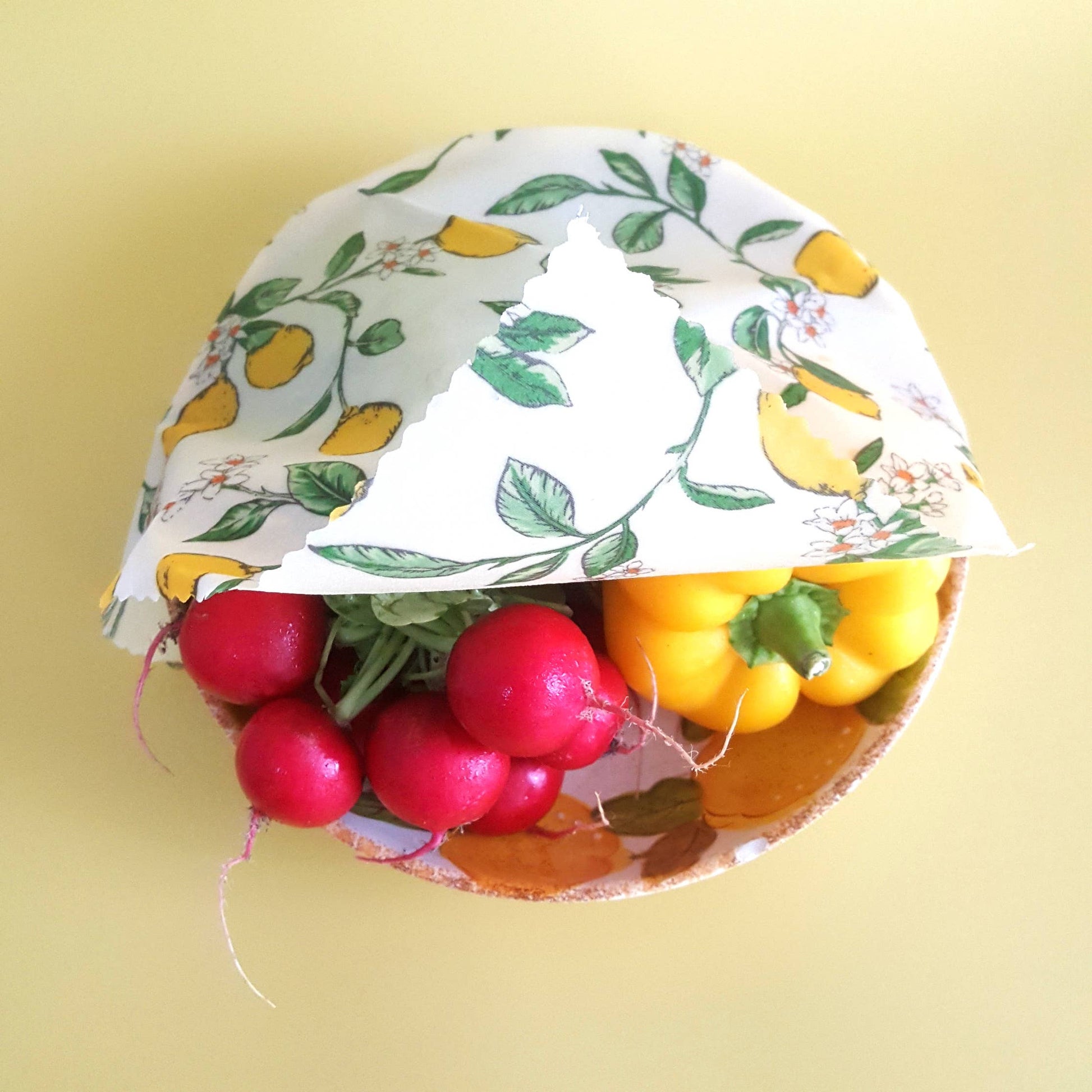 A bowl of vegetables partially covered with a wax food wrap