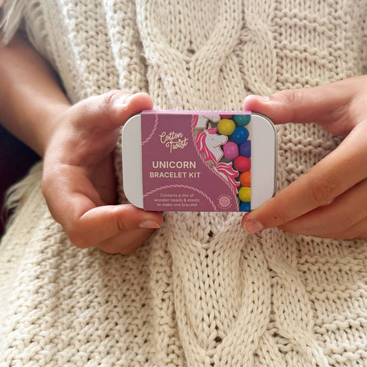 Cotton Twist Unicorn Bracelet Kit held by hands on a knitted fabric background