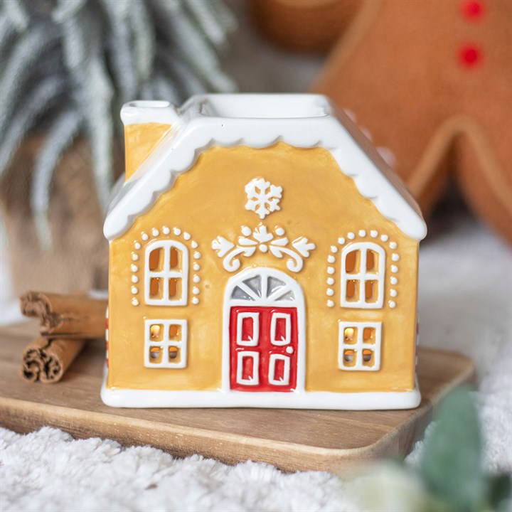 Decorative gingerbread house wax warmer on a wooden board with a blurred background