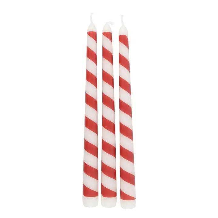 Three red and white striped candles on a white background