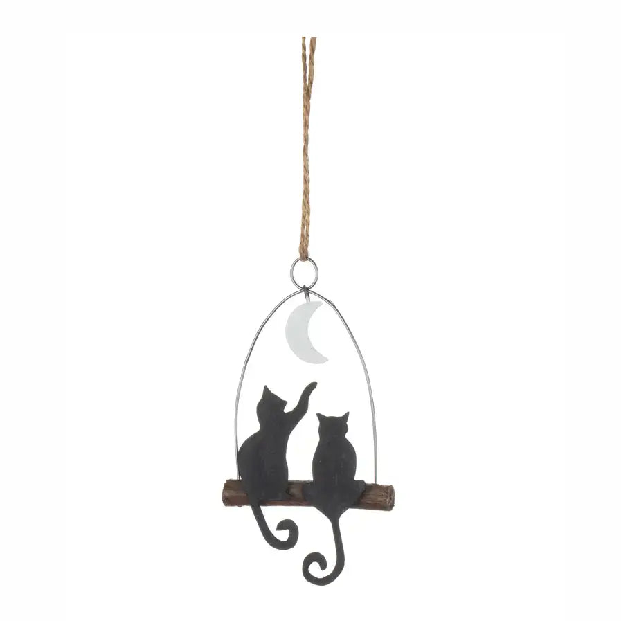 A hanging decorative ornament featuring two black cat silhouettes sitting on a wooden branch under a crescent moon, suspended by a rope against a plain white background.