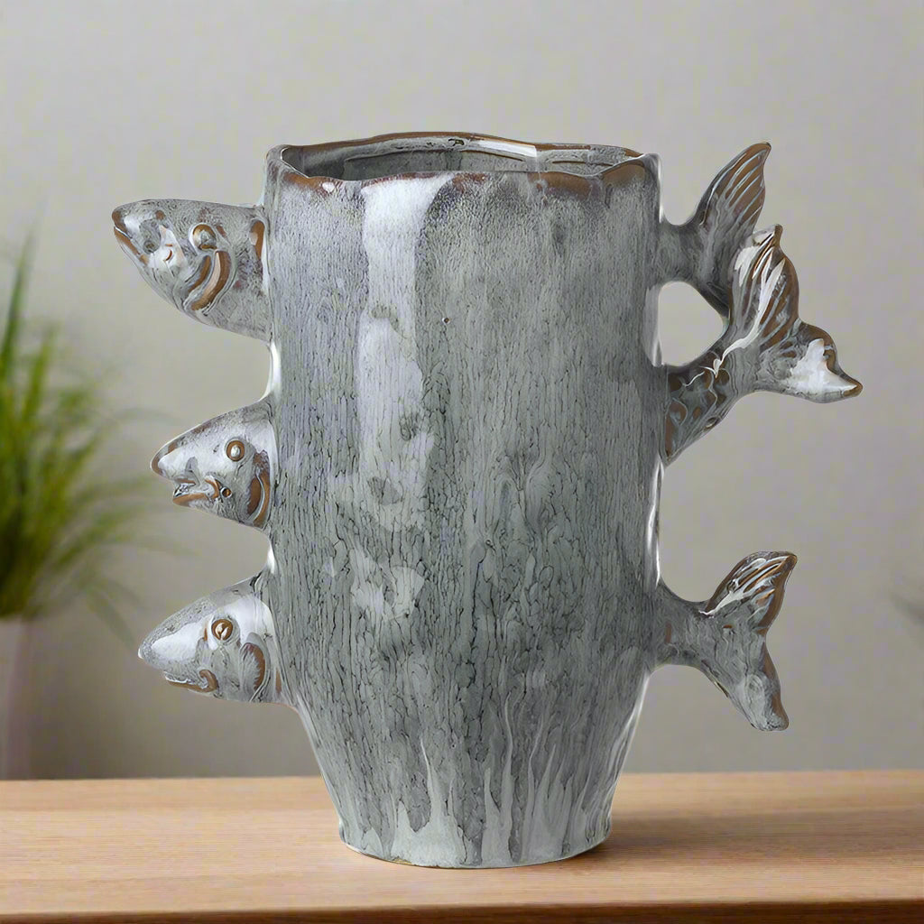 Ceramic blue glaze vase with fish sticking out of it. Tails one side heads on the other