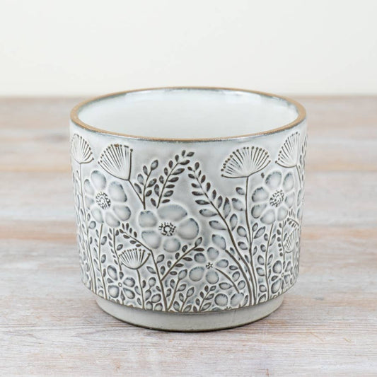 Ceramic planter with floral patterns on a wooden surface