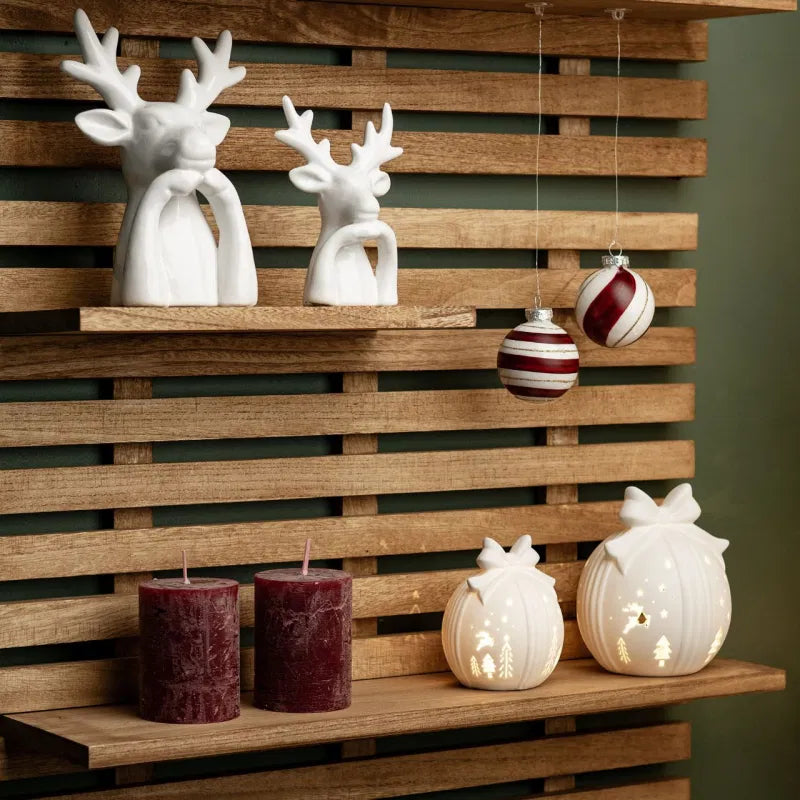 Decorative items including ceramic deer, candles, and hanging ornaments on a wooden shelf.
