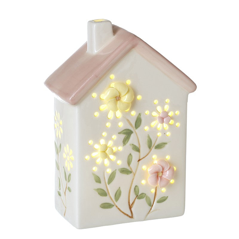 Decorative light shaped like a house with floral designs and glowing lights on a white background.
