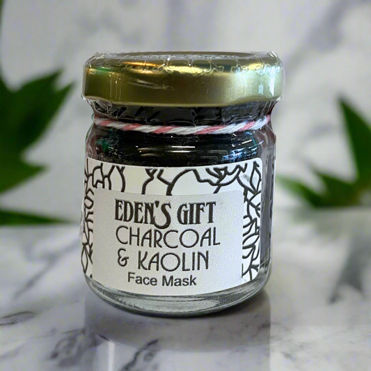 Jar of Eden's Gift Charcoal & Kaolin Face Mask on a marble surface with a blurred plant background