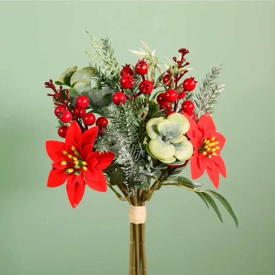 An artificial holiday floral arrangement featuring bright red poinsettias, red berries, green eucalyptus, and frosted white foliage, tied with a beige band at the stem and set against a solid sage green background.