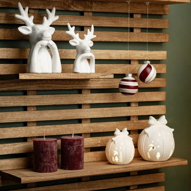 Decorative items including deer figurines, candles, and hanging ornaments on a wooden shelf.