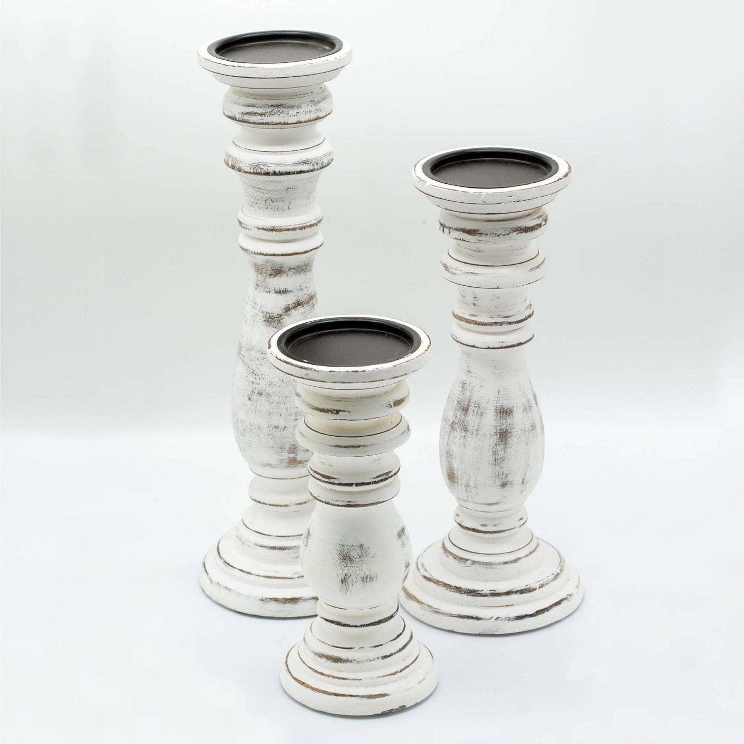 Set of three white distressed candle holders on a light gray background
