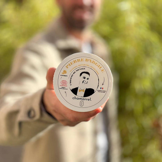 Person holding a container of Pierre d'Argile chamomile product with a blurred green background
