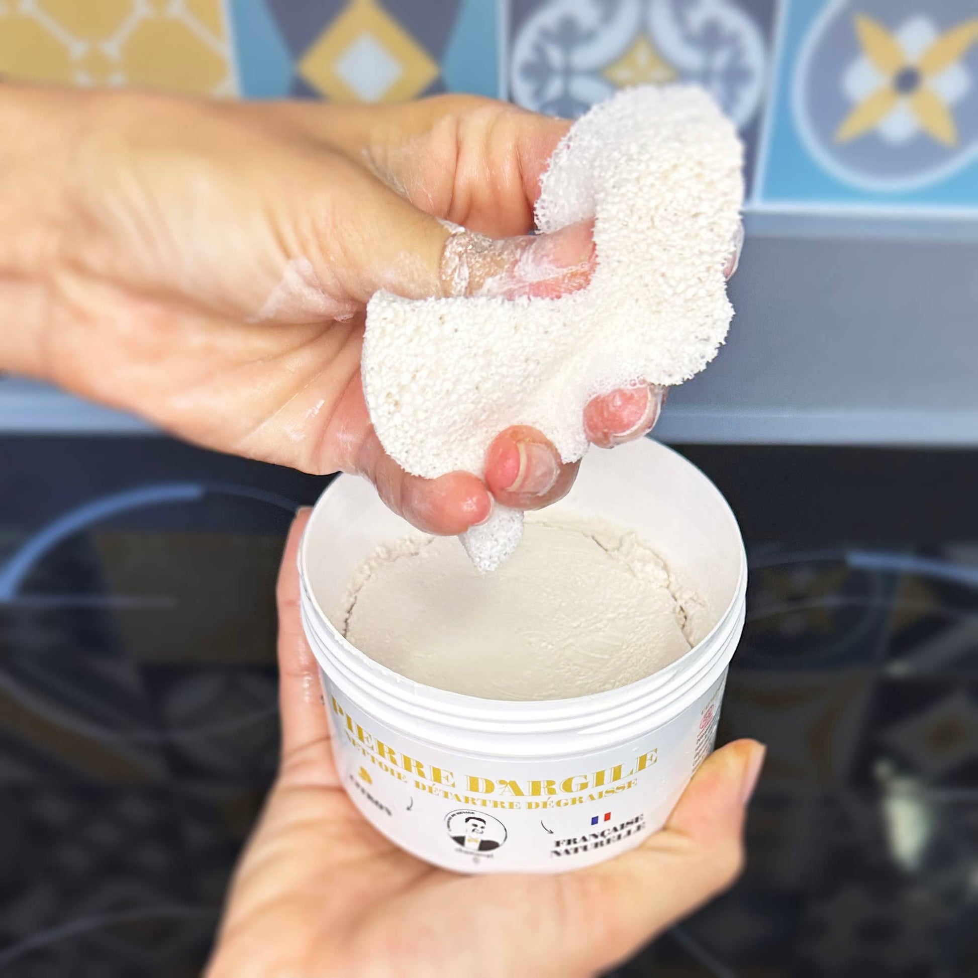 Hand holding a container of white powder with a decorative background