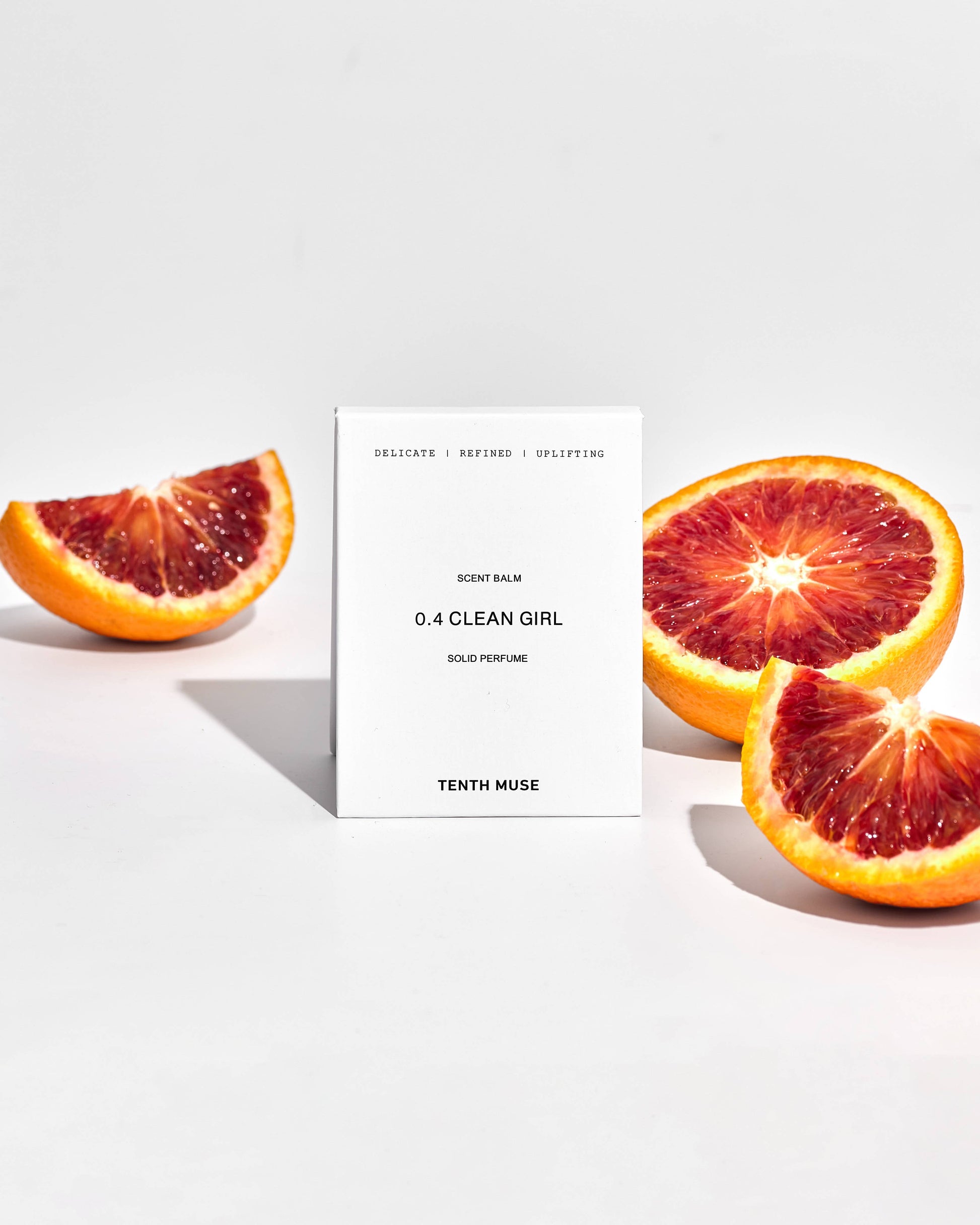 Tenth Muse Clean Girl solid perfume packaging with blood orange slices on a white background