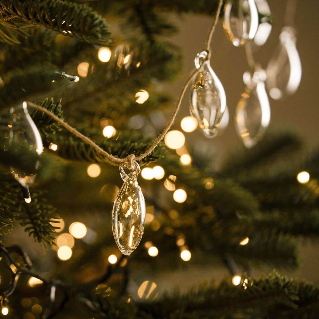 Decorative string of glass baubles hanging on a Christmas tree with a warm glow.