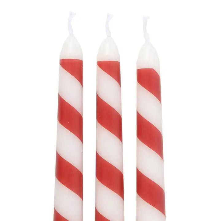 Three red and white striped candles on a white background