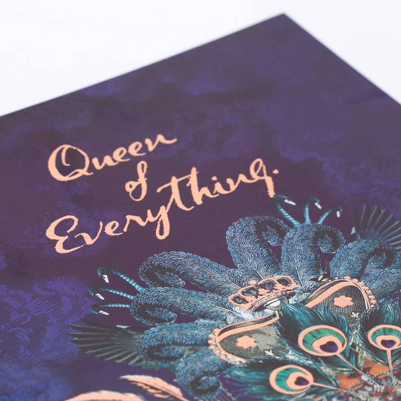 Decorative notebook with peacock feathers and 'Queen of Everything' text on a purple background