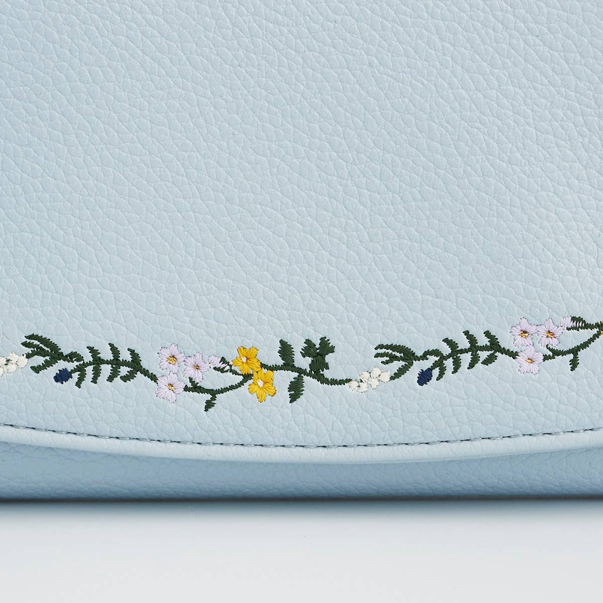 Light blue purse with floral embroidery on a white background