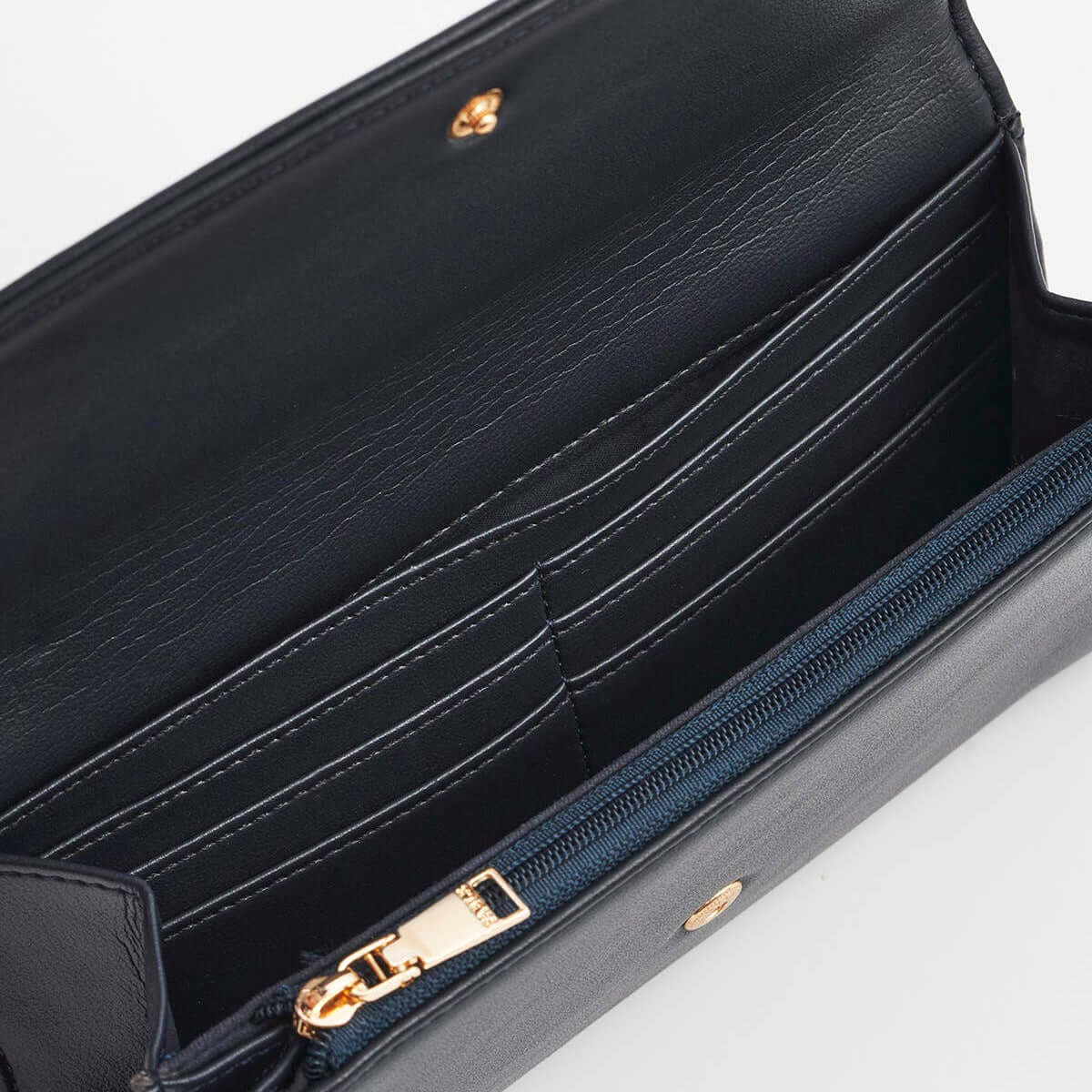 Close-up of an open black leather wallet or clutch showing interior card slots, a zip pocket with a gold-tone zipper pull, and small gold hardware on a light gray background.