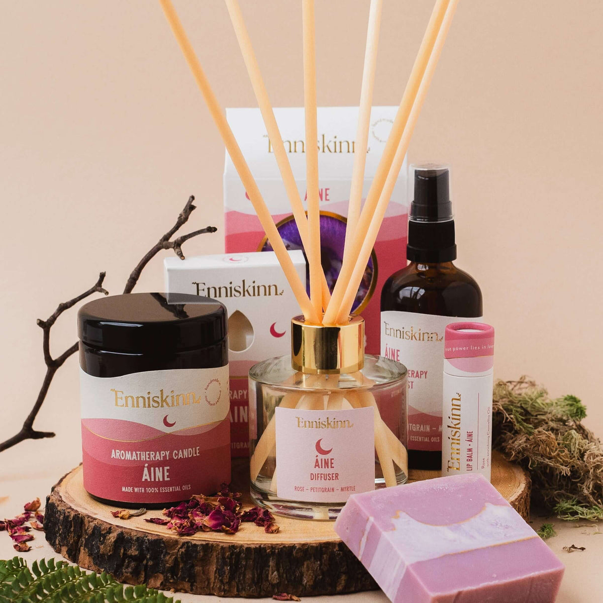 Collection of Enniskin skincare products including a candle, soap, and diffuser on a wooden stand.