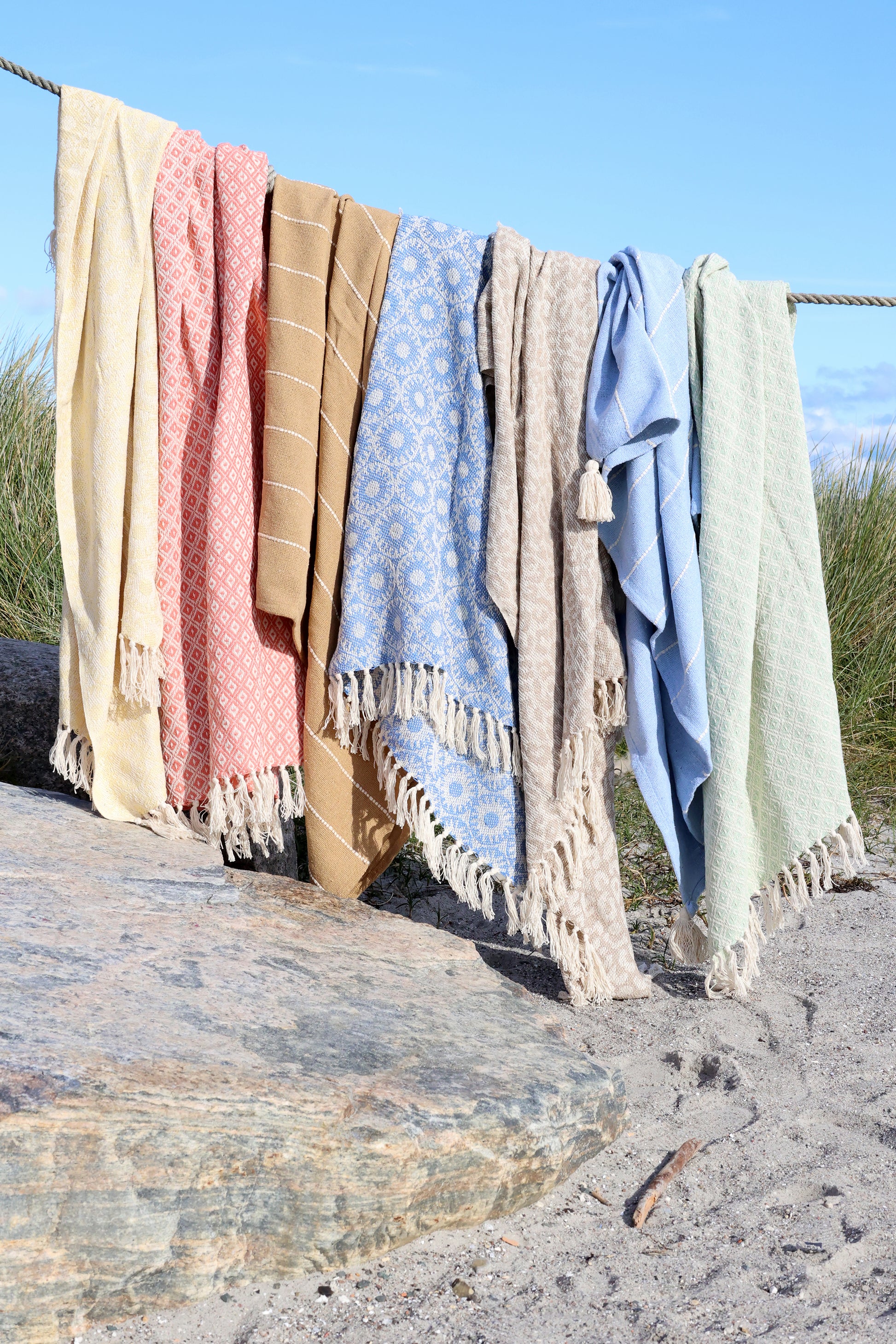 Colorful towels hanging on a line with a beach background