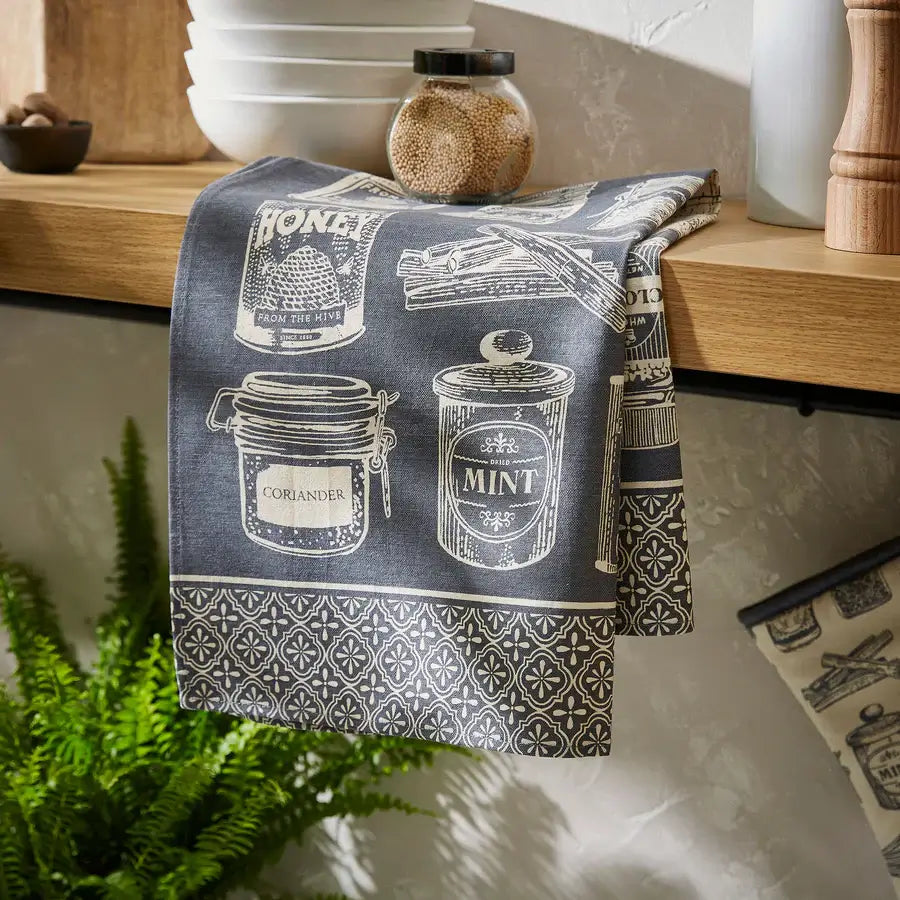 Kitchen towel with jar design hanging on a wooden shelf.