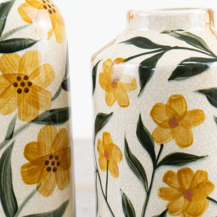 Two ceramic vases with yellow floral patterns on a white background
