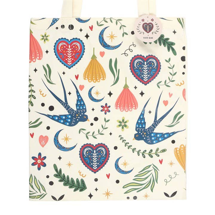 Tote bag with colorful pattern of hearts, birds, and flowers on a white background