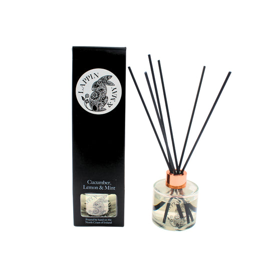 Reed diffuser with black sticks and a clear container on a white background