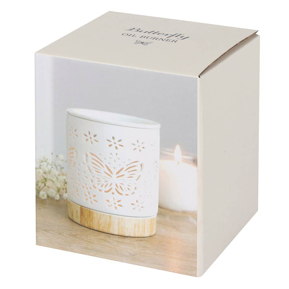 Butterfly oil burner in a decorative box with floral elements.